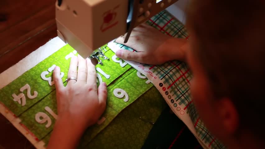 A woman sewing a Christmas advent calendar in her home