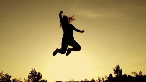 SLOW MOTION: young woman jumping at sunset