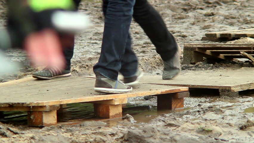 People step on wooden platform walking over dirty place