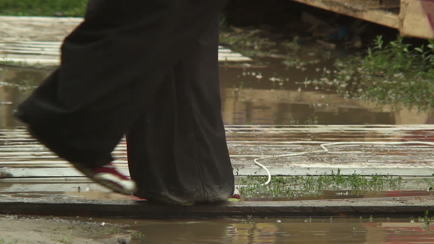 Backwash of flood, people legs walking on puddles climate change