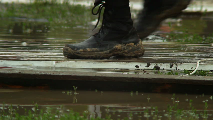 Massive military boots step on wooden platform over water, flood