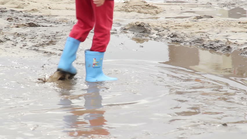 Child feet walk on puddle dirt, blue boots, children unsafety