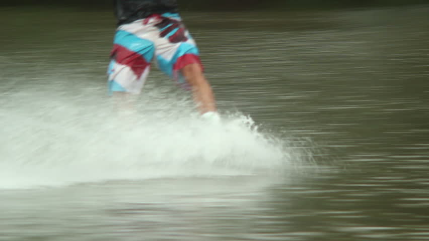 Action water sports, wakeboarder male legs ride on water surface