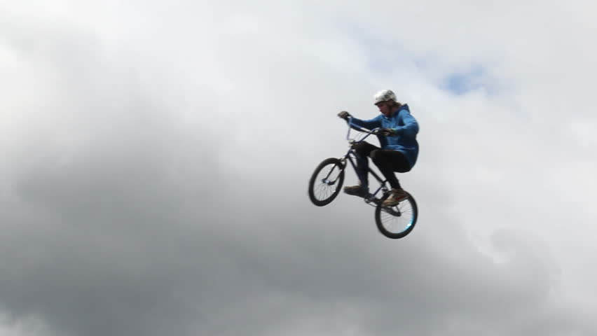 BMX bicycle man jumps high cloudy background slow motion