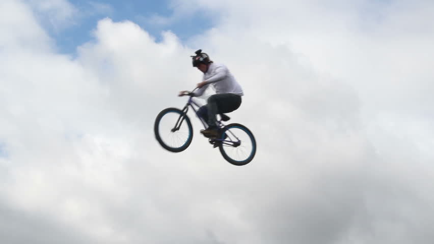 Slow motion bicycle jumper jumps high with bike sky background