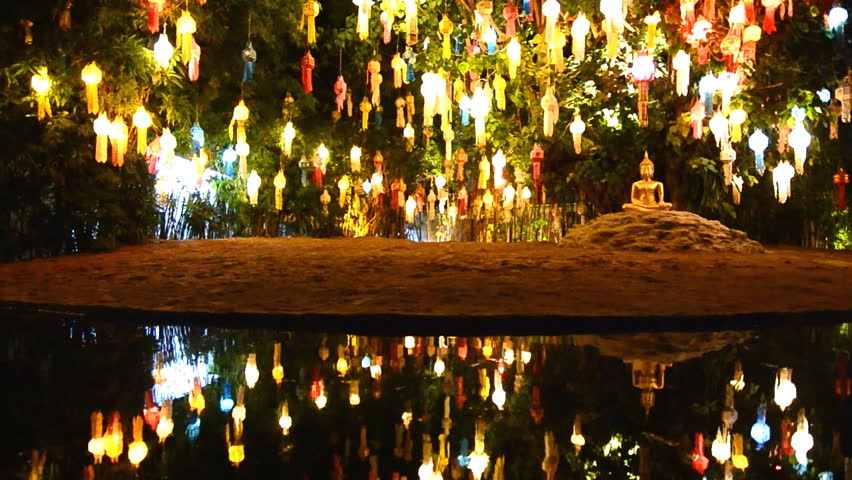 gold buddha image under beautiful lantern tree and reflection of pond (zoom out)