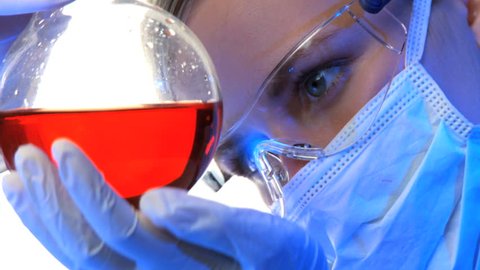 Close up of female scientist examines vial with blood 