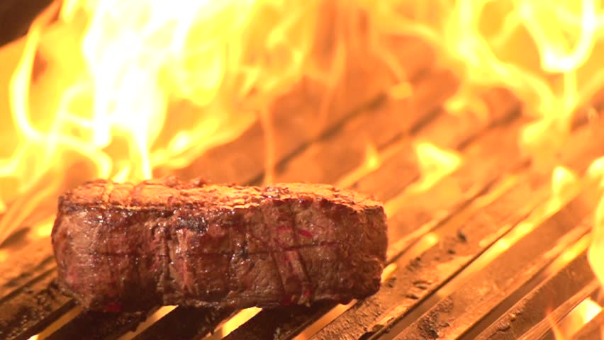 Steak on grill with flames in background