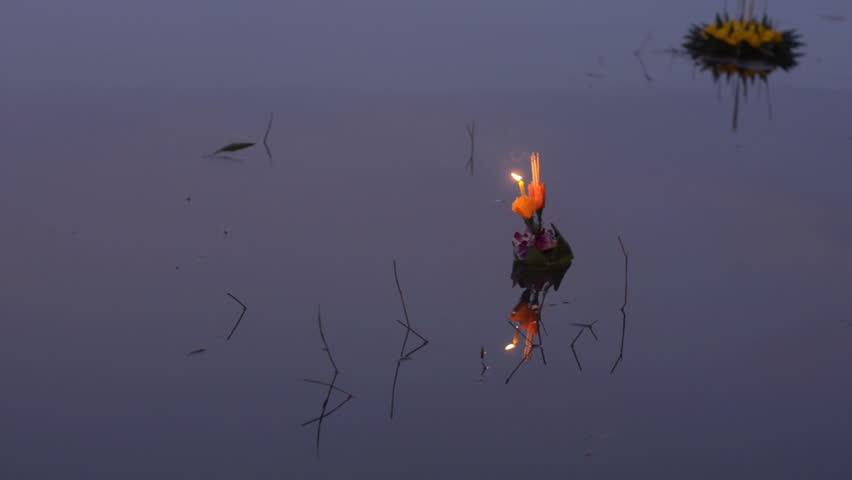 A small krathong floating by in the grey light of dusk during the Loi Krathong