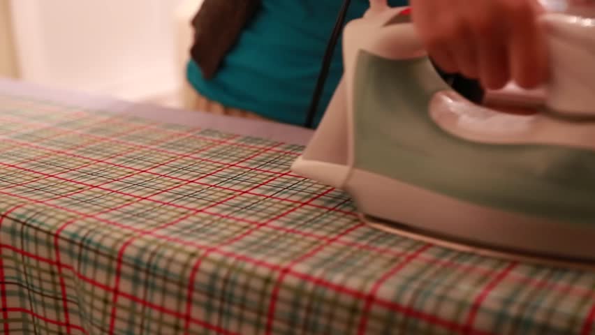 A woman irons fabric on the ironing board