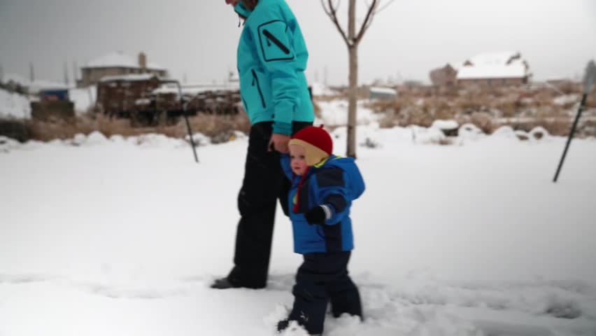 A mother and her baby boy playing in the snow after a winter storm
