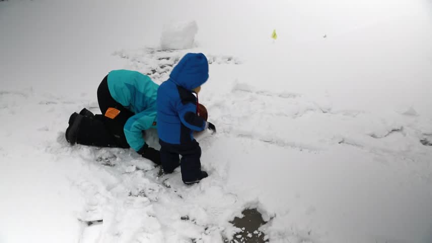 A mother and her baby boy playing in the snow after a winter storm