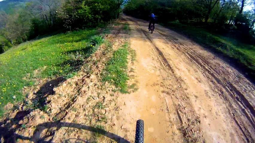 Mountain biker riding down on main road in pursuit of other mountain bikers pov