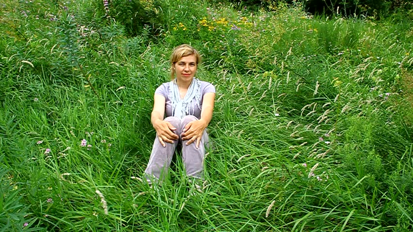 Happy woman lying on green grass in a meadow