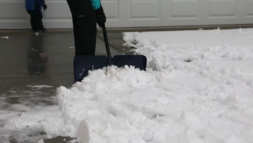 A mother and her baby boy shoveling snow off the driveway after a large