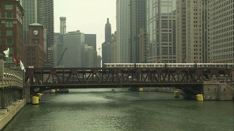 An elevated train crosses a bridge spanning the Chicago river