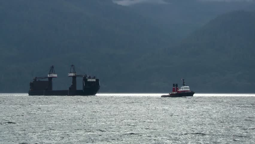 Tug boat pulling a crane across Telegraph Cove.