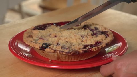 Close up of woman's hands cutting a slice of fruit pie and putting on plate, nice shallow depth of field : vidéo de stock