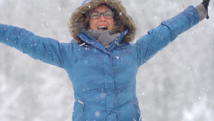 Slow Motion Of Young Woman Jumping Up With Joy Outdoors While It is Snowing. 