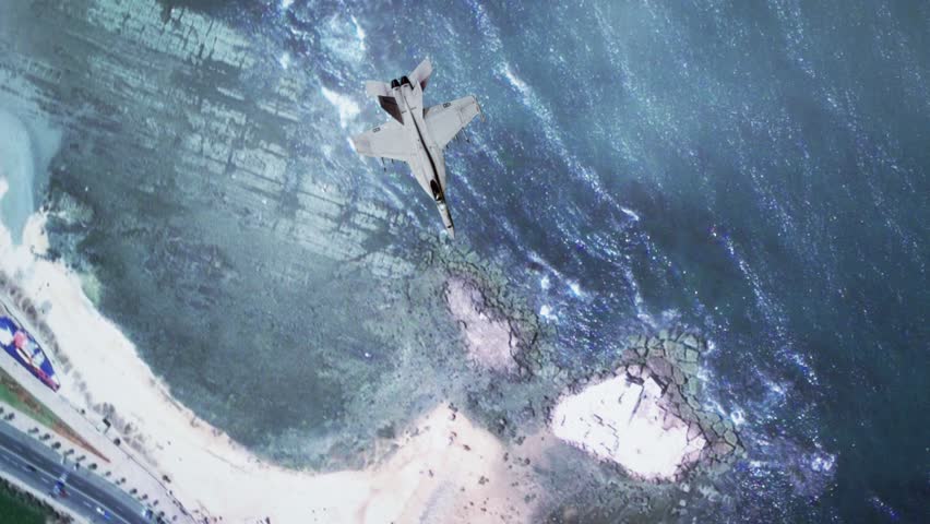 Overhead shot of F-18 Military Aircraft flying through clouds over land and water