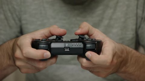 Man playing with a videogame controller in his hands. Focus on the controller
