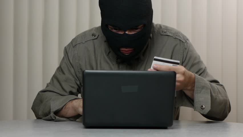Mask criminal with a laptop computer and a stolen credit card. Great video for
