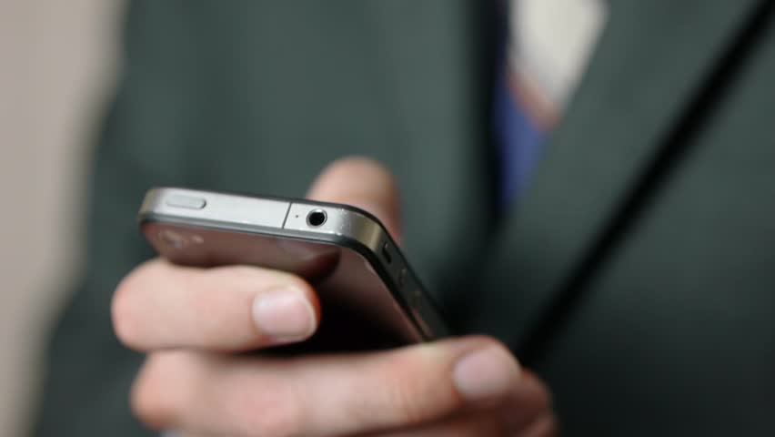Closeup on a businessman browsing messages on his last generation smartphone.