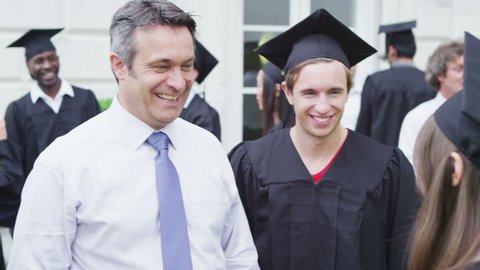 Happy students on graduation day are hugged and congratulated by proud parents Stock Video
