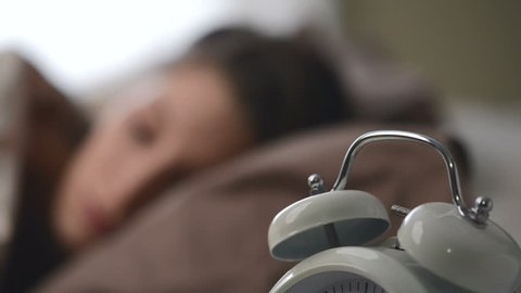 A young woman is woken by her alarm clock