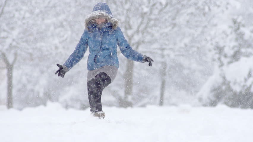 Slow Motion Of Young Woman Having Fun Kicking Snow During Blizzard In Park