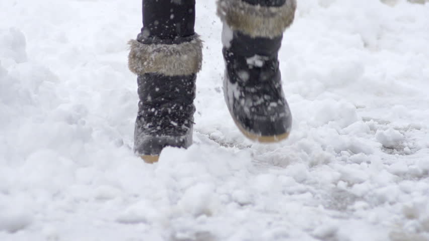 Slow Motion Of Female Legs Wearing Black Snow Boots Walking Though Fresh Snow On