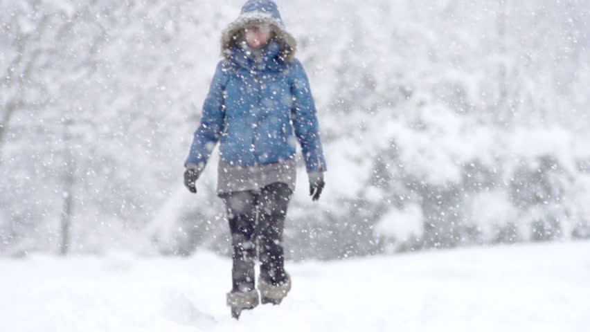 Slow Motion Front View Of A Young Woman Walking Through Fresh Snow. Outstretches