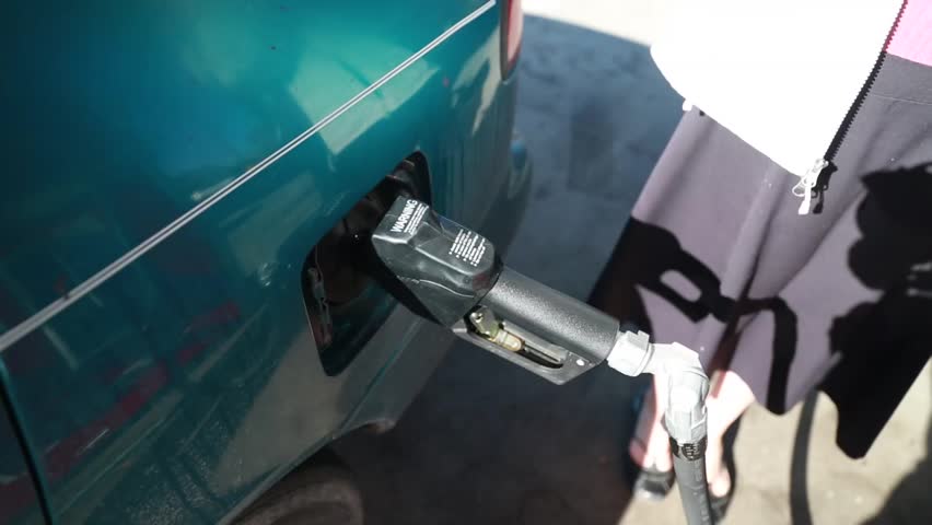 A woman pumping gas at the gas station pump