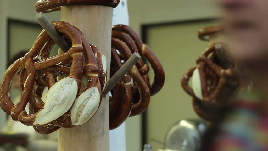 Big bagels are hung on a nail on a pole at pastry.A pretzel is a type of baked bread product made from dough most commonly found in a unique knot-like shape often claimed to represent hands in prayer 