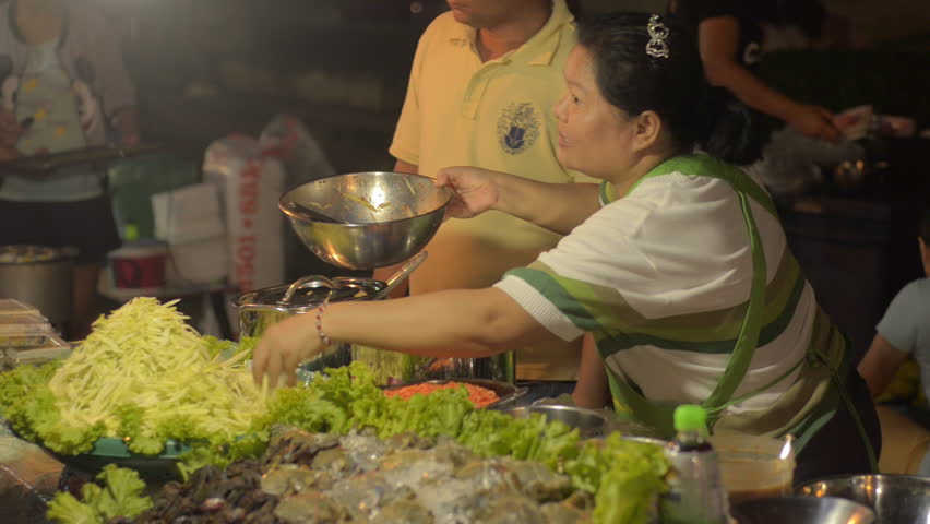 BANGKOK, THAILAND - NOVEMBER 2013: A Thai street vendor making green mango salad