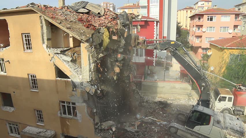 Apartment building demolition using an excavator with telescopic arm attachment.