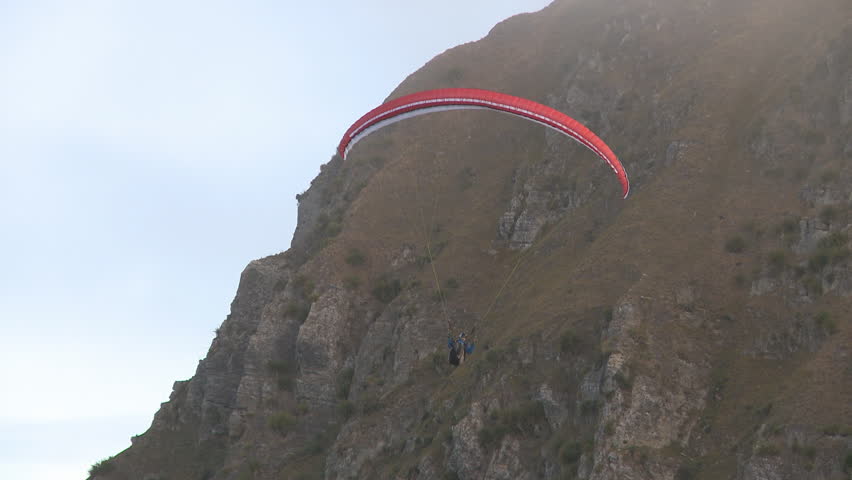 A paraglider soaring along a ridge line gains lift. 