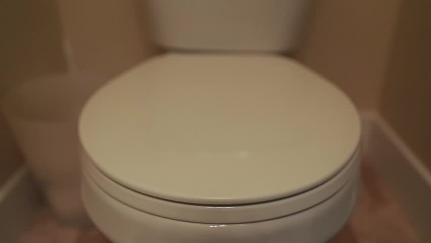 A hand lifting the toilet lid