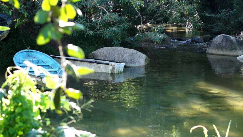 Scenic dolly shot of boats floating on a tranquil river on a sunny day.