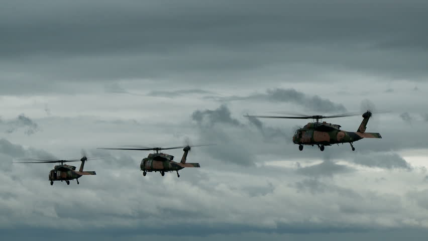 Three blackhawk helicopters hover before departing in formation