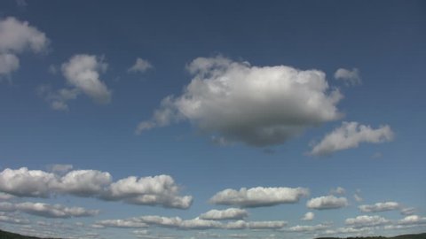 Cumulus cloud landscape. Timelapse. Clean with no birds! Nice spot at top for copyspace.  Wide angle shot with landscape visible at bottom right and left edges of frame. 