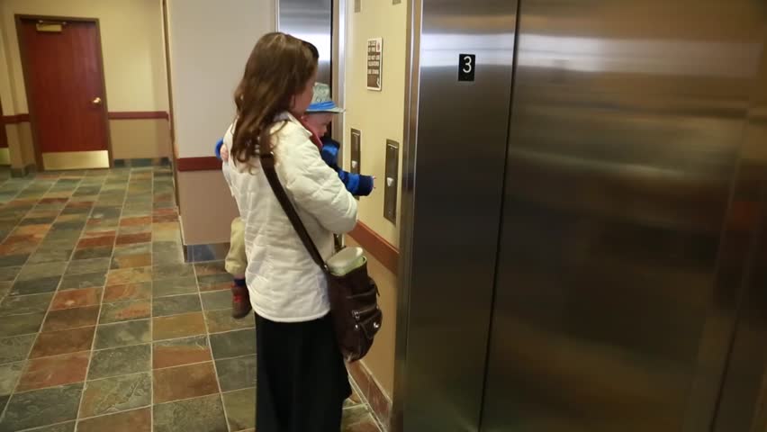 A mother and her baby getting on the elevator in a building