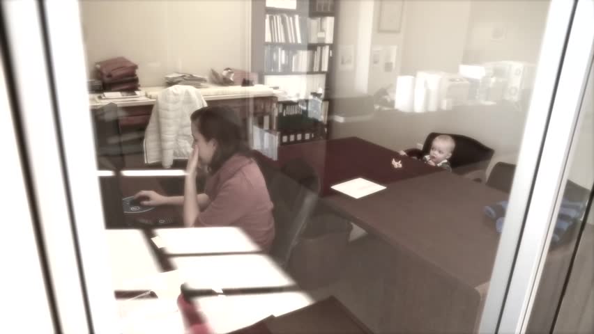 A mother working in the office with her little toddler boy by her side