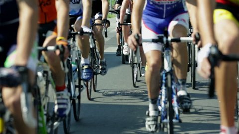 Shallow focus shot of cyclists lower bodies while riding bikes in cycling race