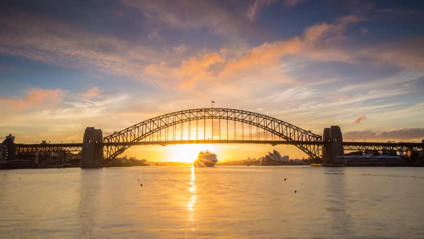 SYDNEY - AUSTRALIA - NOVEMBER 20: (Timelapse) A beautiful sun rises over Sydney Harbour revealing the Bridge and Opera House welcoming new visitors as a large cruise ship enters on Novermber 20, 2013.