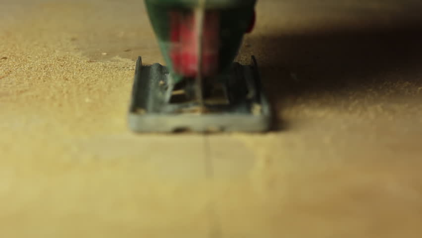 Electric fretsaw is sawing plywood. Close-up. Front view