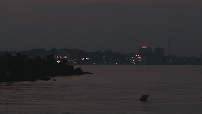 Night over the seaside, lighted touristic town in background