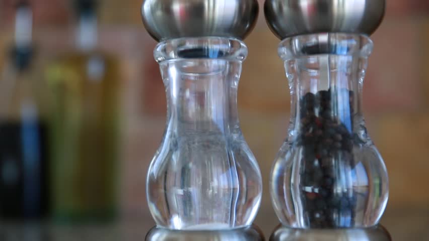 A hand grabs salt and pepper shakers off the kitchen counter