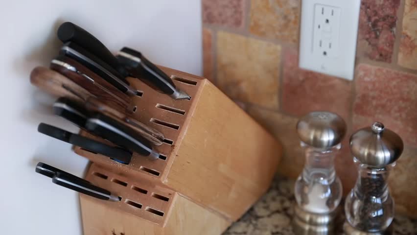 A man uses knifes from a knife block in a kitchen