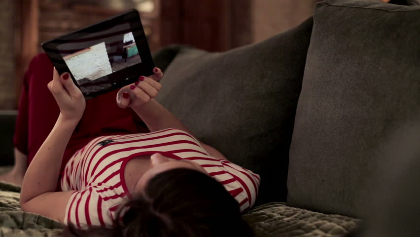 Young woman watching photos on tablet computer on sofa
